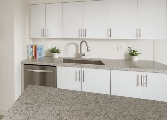 A kitchen with white cabinets and a granite countertop.