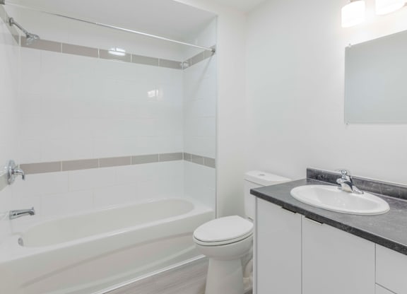 A white bathroom with a toilet, sink, and bathtub.