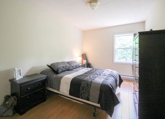 A bedroom with a bed, nightstand, and window.