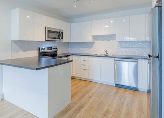 A modern kitchen with white cabinets and a black countertop.