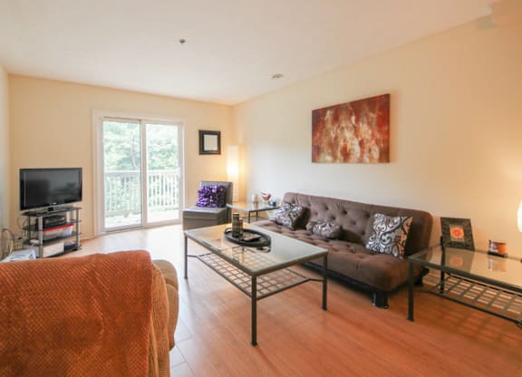A living room with a brown couch and a glass coffee table.