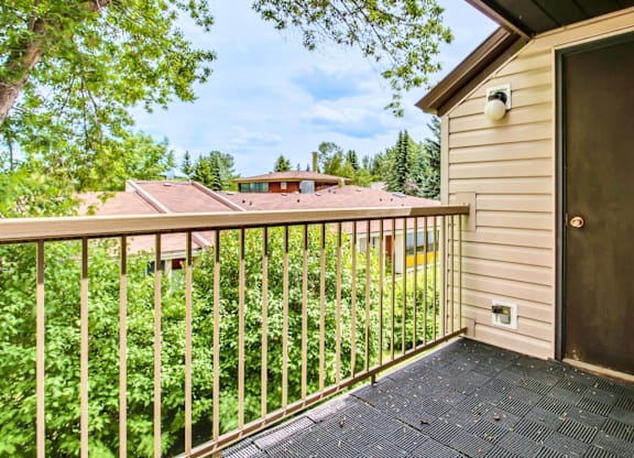 A balcony with a view of a house and trees.