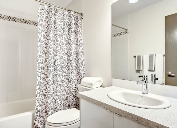A white bathroom with a sink, toilet, and shower curtain.