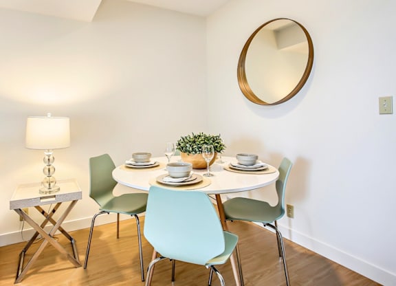 A white dining table with four chairs and a small plant on it.
