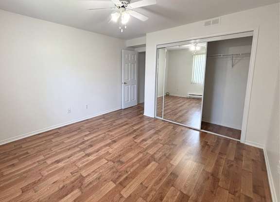 A room with a ceiling fan and wooden flooring.