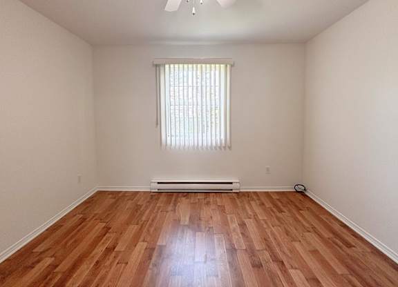 A room with wooden flooring and a ceiling fan.