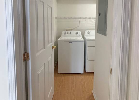 A white door is open to a laundry room with a washer and dryer.