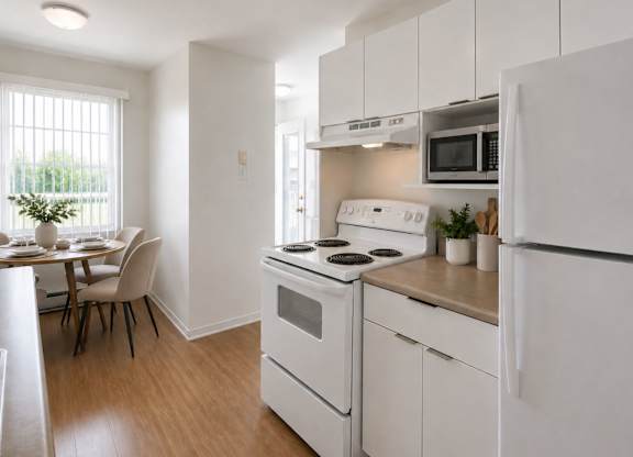 A white kitchen with a stove, refrigerator, and dining table.