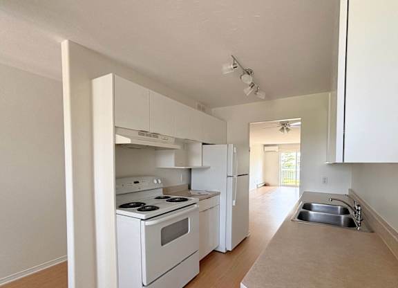A white kitchen with a stove, oven, and refrigerator.