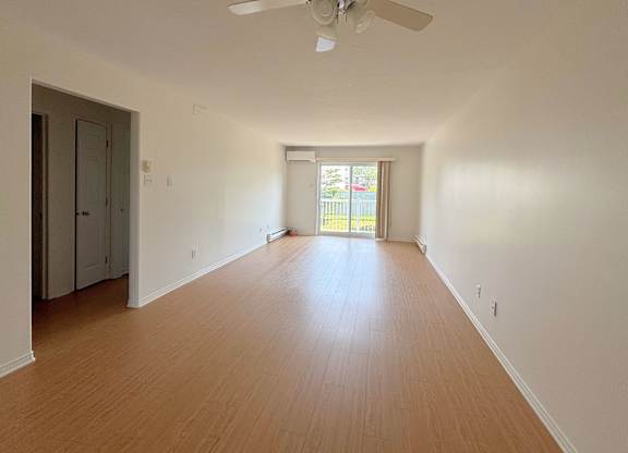 A room with a ceiling fan and wooden flooring.