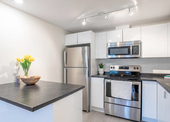 A modern kitchen with a stainless steel refrigerator, oven, and microwave.