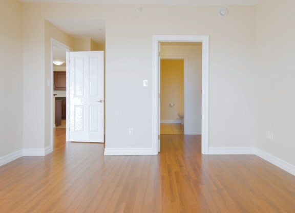 A room with a white door and a wooden floor.
