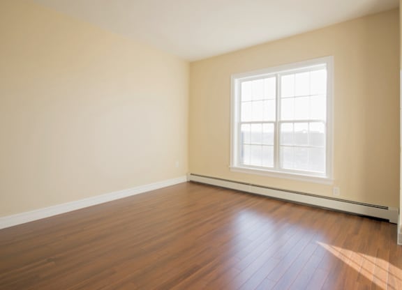 A room with a window and wooden flooring.