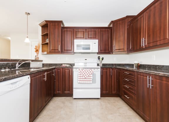 A kitchen with brown cabinets and white appliances.