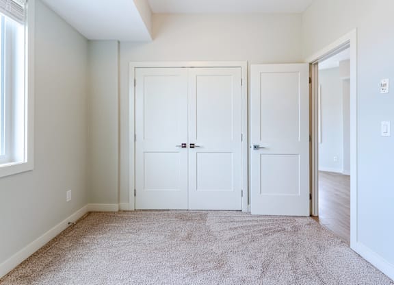 A room with two white doors and a carpeted floor.