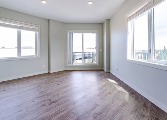 A room with wooden floors and two windows.