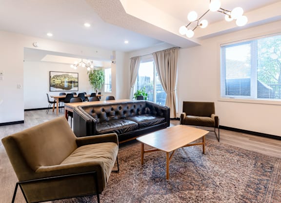 A living room with a black couch, brown armchair, and a wooden coffee table.