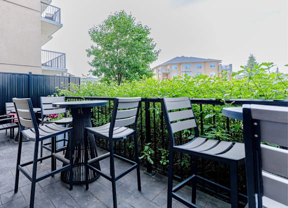 A patio with a table and chairs surrounded by greenery.