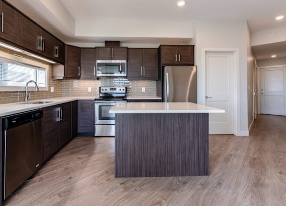 A modern kitchen with dark wood cabinets and stainless steel appliances.