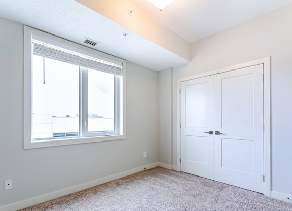 A room with a white door and a window with blinds.
