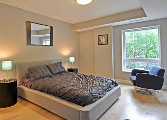 A bedroom with a large bed and a chair.
