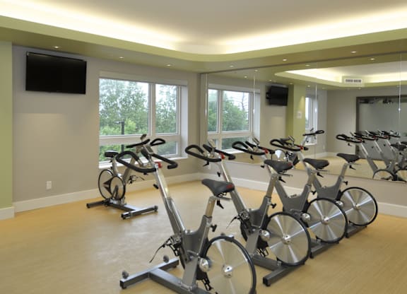 A room with exercise bikes and a television on the wall.