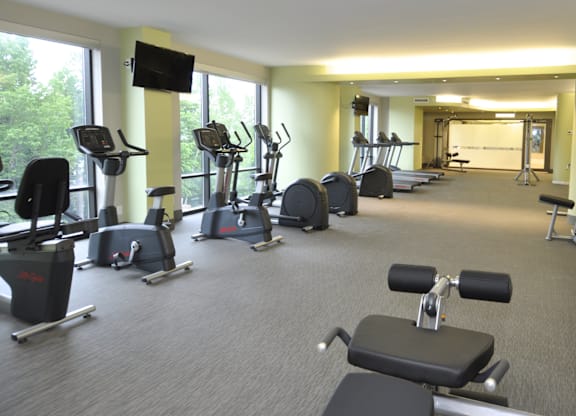 A gym with a variety of exercise equipment including treadmills, stationary bikes, and weight machines.