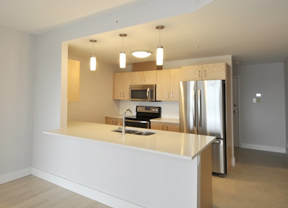 A modern kitchen with a refrigerator, microwave, and oven.