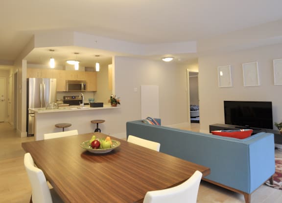 A modern dining room with a wooden table and white chairs.