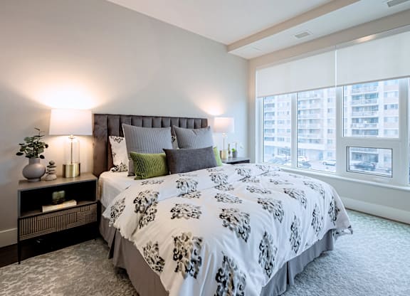 A bedroom with a large bed and a window overlooking a cityscape.