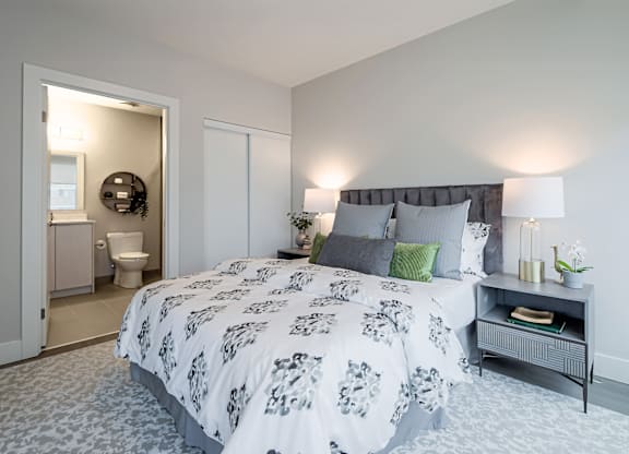 A bedroom with a large bed and a nightstand with a lamp.