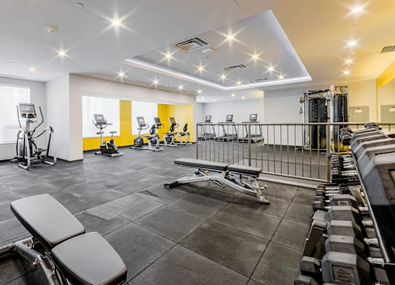 A well-lit gym with various exercise equipment.