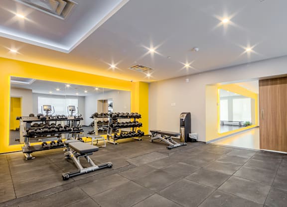 A gym with a variety of equipment including weights and benches.