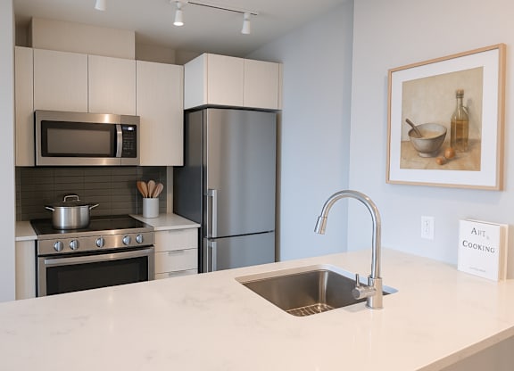 A modern kitchen with a stainless steel refrigerator and a marble countertop.