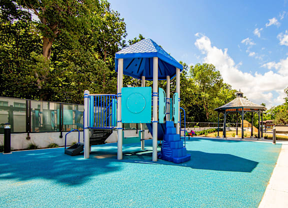 A playground with a blue slide and a gazebo.