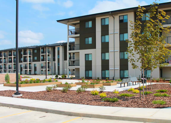 A modern apartment complex with a landscaped courtyard in front.