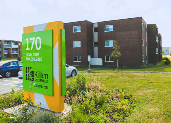 A sign for Killam Apartment Rent in front of a building.
