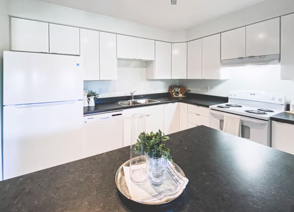 A kitchen with white cabinets and a black countertop.