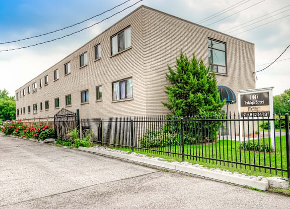 A building with the number 1447 on it is surrounded by a black fence.