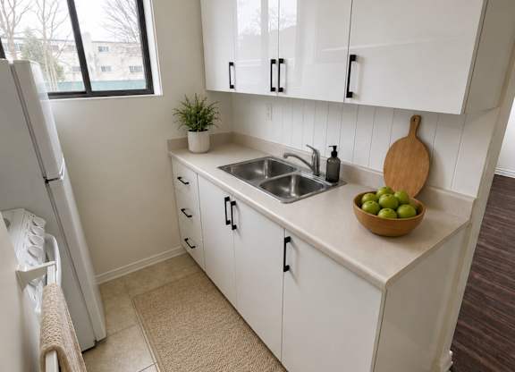 A kitchen with white cabinets and a bowl of green apples on the counter.