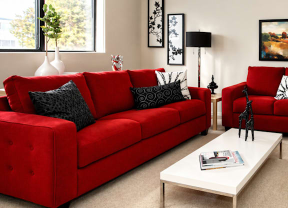 A red couch with a white coffee table in front of it.