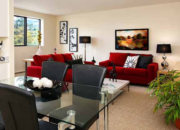 A modern living room with a glass dining table and red couch.