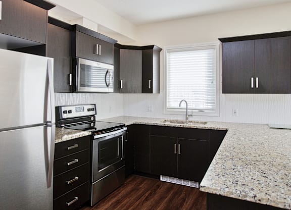 A kitchen with black cabinets and a granite countertop.