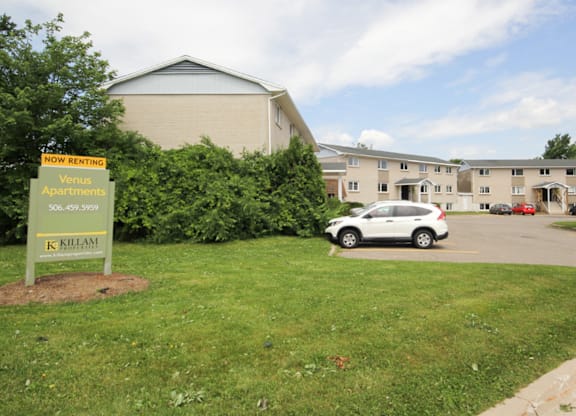 A sign in front of a building advertises that it is now renting.