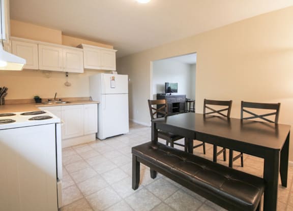 A kitchen with a white refrigerator and a black table.