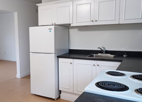 A white fridge in a kitchen with black countertops.