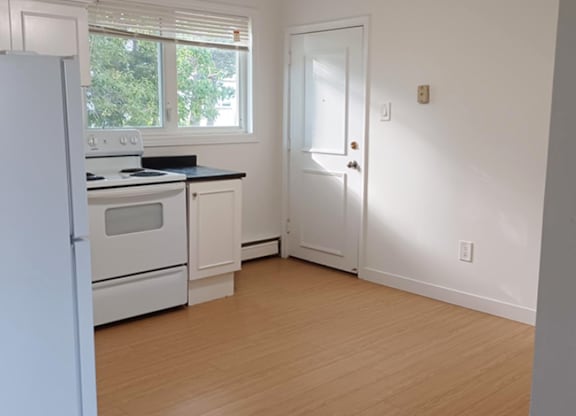 A kitchen with white appliances and a white door.