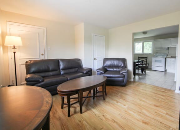 A living room with a black leather couch and a wooden table.