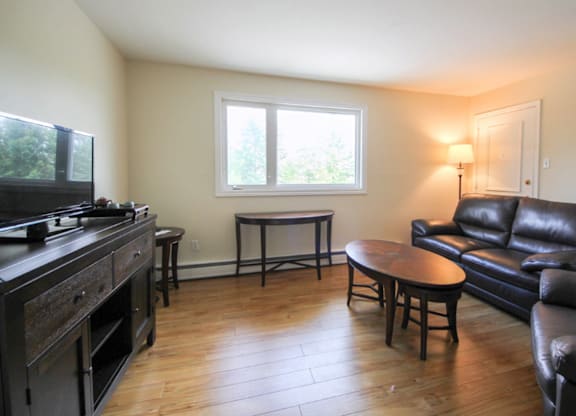 A living room with a black leather couch and a wooden coffee table.