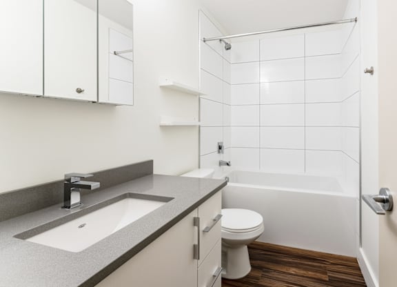 A white bathroom with a sink, toilet and shower.
